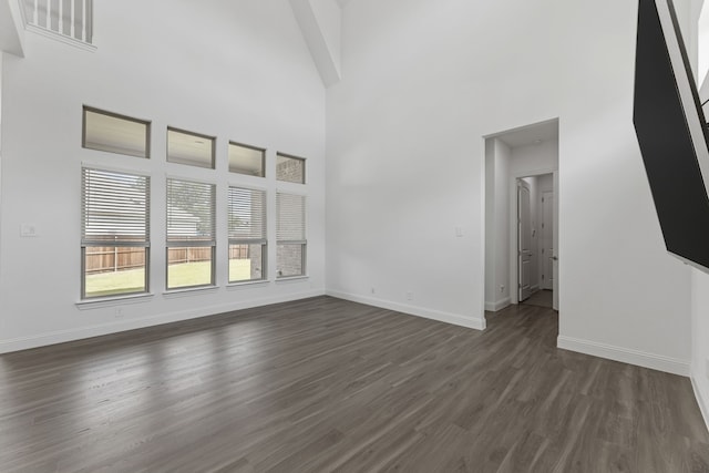 unfurnished living room featuring a high ceiling and dark hardwood / wood-style flooring