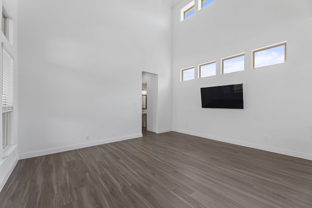 unfurnished living room with a towering ceiling and dark hardwood / wood-style flooring