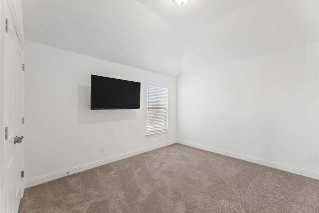 carpeted spare room with vaulted ceiling