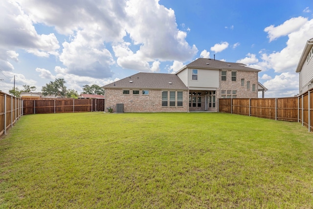 rear view of property with central AC and a yard