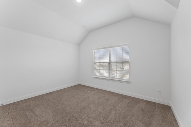 unfurnished room with lofted ceiling and carpet flooring