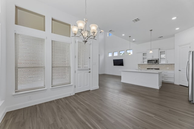 kitchen featuring hanging light fixtures, stainless steel appliances, a kitchen island with sink, backsplash, and white cabinetry