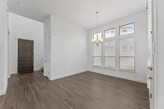 unfurnished dining area with dark wood-type flooring and an inviting chandelier