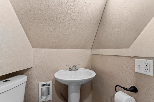 bathroom featuring lofted ceiling, toilet, and sink