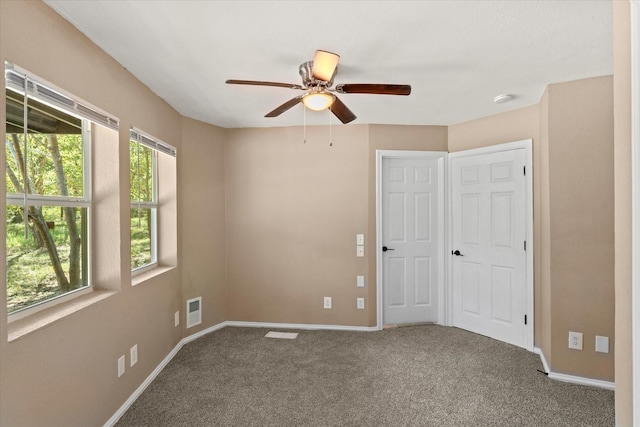 carpeted spare room featuring ceiling fan and a healthy amount of sunlight