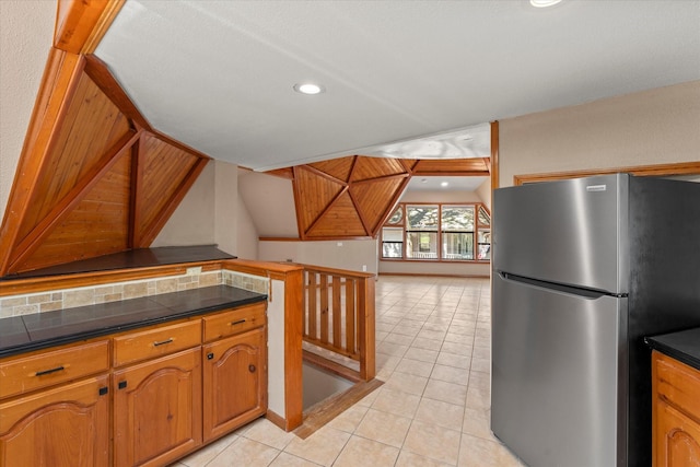 kitchen featuring stainless steel refrigerator, light tile patterned floors, and tasteful backsplash