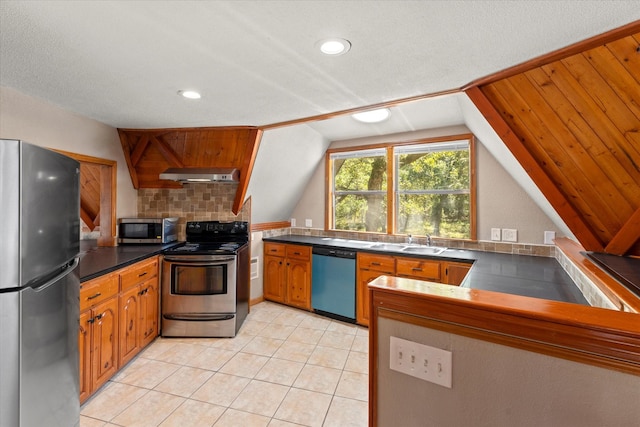 kitchen featuring kitchen peninsula, range hood, vaulted ceiling, stainless steel appliances, and sink