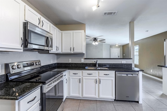 kitchen featuring kitchen peninsula, stainless steel appliances, white cabinetry, light tile patterned flooring, and sink