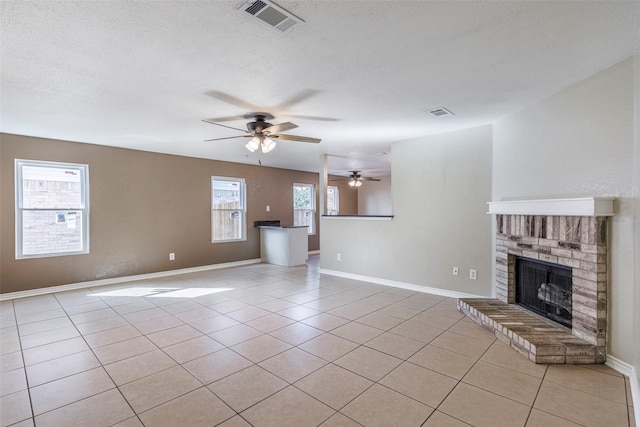 unfurnished living room featuring a textured ceiling, a fireplace, and light tile patterned floors