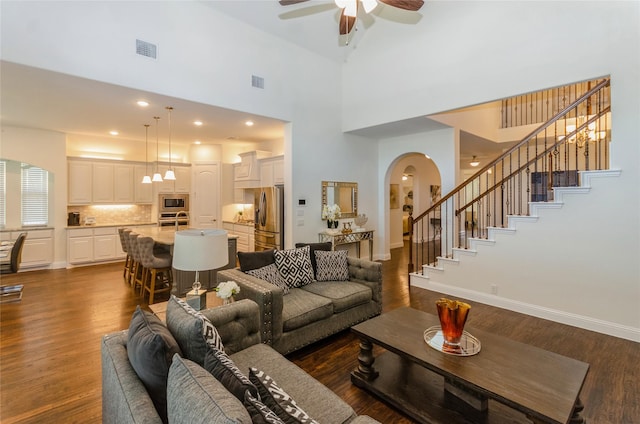 living room with high vaulted ceiling, ceiling fan, and dark wood-type flooring