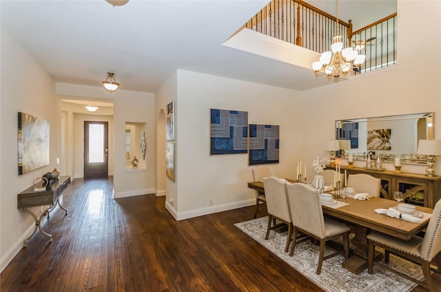 dining room featuring a towering ceiling, dark hardwood / wood-style flooring, and a chandelier