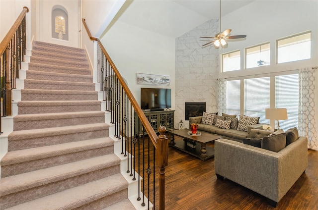 living room with high vaulted ceiling, a tiled fireplace, ceiling fan, and dark hardwood / wood-style flooring