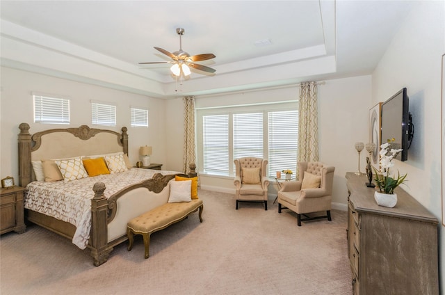 bedroom featuring light carpet, ceiling fan, and a tray ceiling