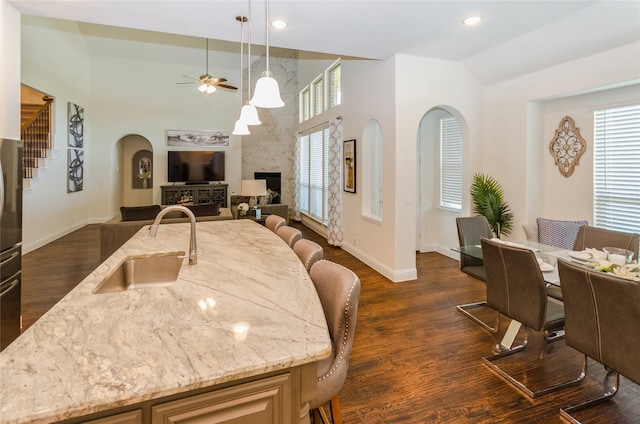 kitchen featuring dark hardwood / wood-style floors, an island with sink, a kitchen bar, ceiling fan, and sink