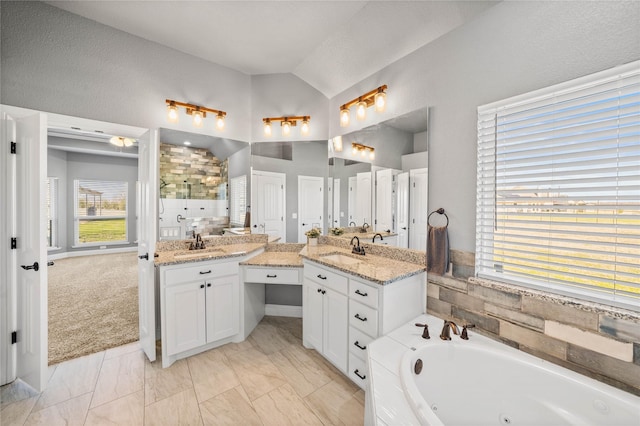 bathroom with a bathtub, vanity, and vaulted ceiling