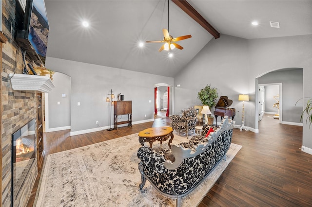 living room featuring dark hardwood / wood-style floors, a brick fireplace, high vaulted ceiling, beam ceiling, and ceiling fan