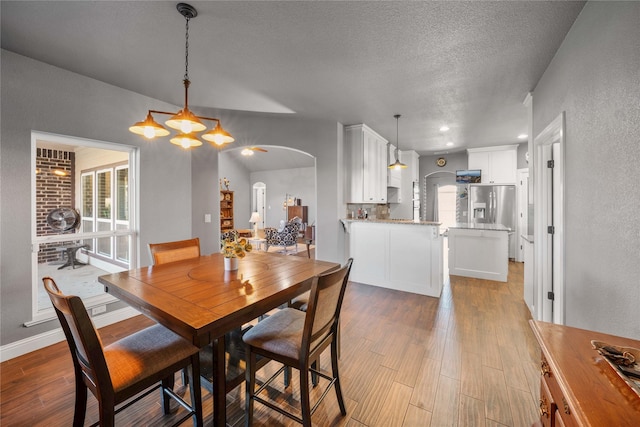 dining area with a textured ceiling, a chandelier, and light hardwood / wood-style floors