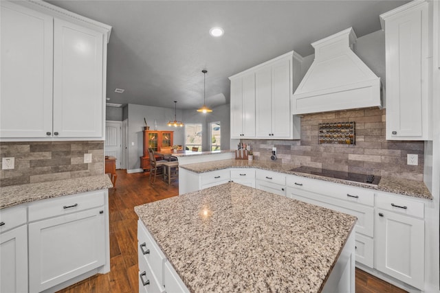 kitchen featuring custom exhaust hood, black electric stovetop, a kitchen island, and hanging light fixtures