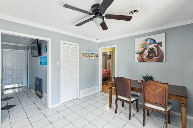 dining area featuring a textured ceiling, ceiling fan, light tile patterned floors, and crown molding