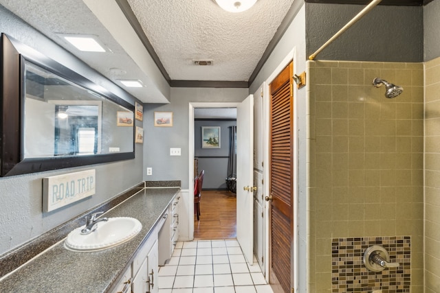 bathroom featuring a textured ceiling, tile patterned floors, a tile shower, and vanity