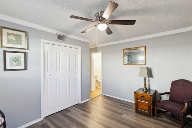 sitting room featuring a textured ceiling, dark hardwood / wood-style flooring, crown molding, and ceiling fan