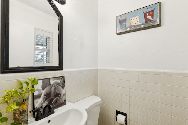 bathroom featuring toilet and tile walls