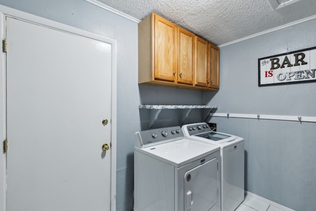 laundry room featuring washing machine and dryer, a textured ceiling, ornamental molding, and cabinets