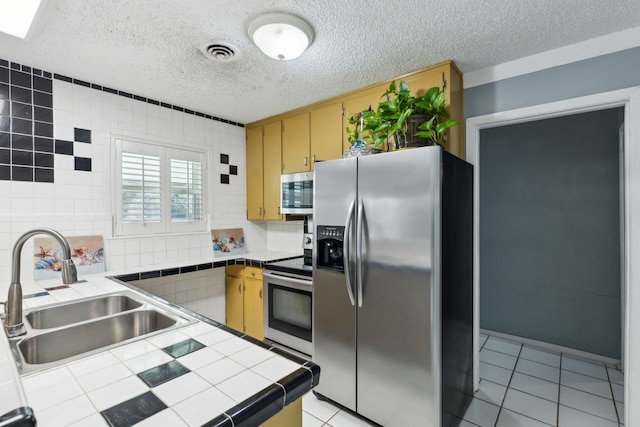 kitchen featuring sink, tasteful backsplash, light tile patterned floors, tile counters, and appliances with stainless steel finishes