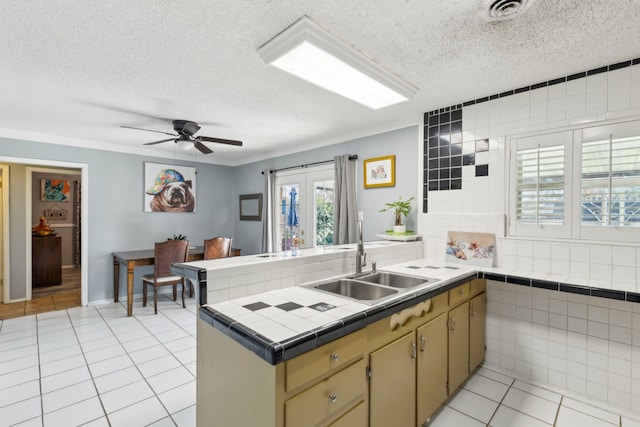 kitchen with sink, backsplash, kitchen peninsula, and light tile patterned floors