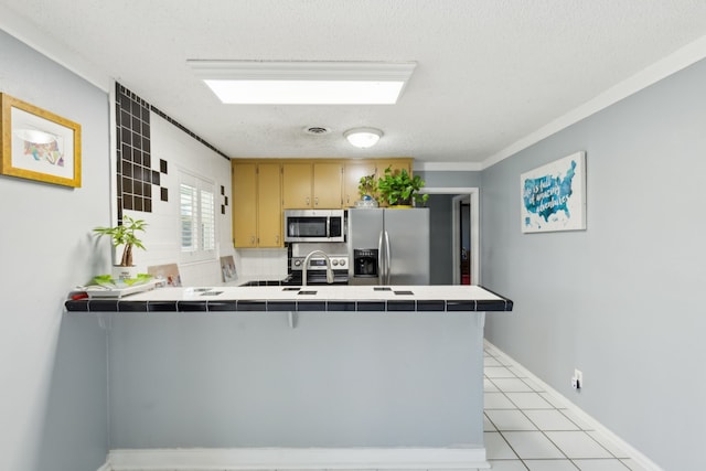 kitchen with stainless steel appliances, tile countertops, and kitchen peninsula