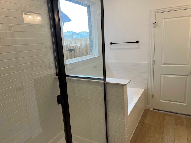 bathroom featuring wood-type flooring, tile walls, and independent shower and bath