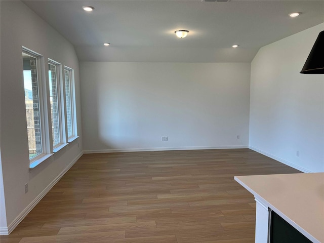 empty room with lofted ceiling and light hardwood / wood-style flooring