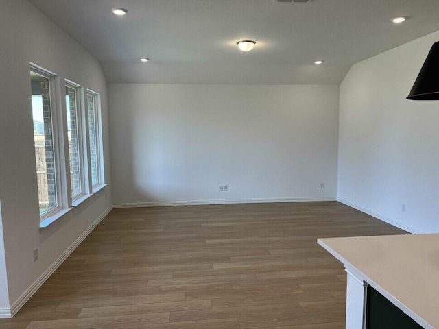 spare room featuring hardwood / wood-style flooring and vaulted ceiling