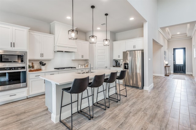 kitchen with white cabinets, stainless steel appliances, and premium range hood