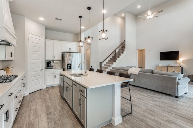 kitchen featuring sink, white cabinets, a kitchen island with sink, and appliances with stainless steel finishes