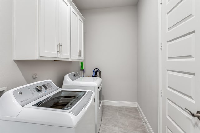 clothes washing area featuring cabinets and washing machine and dryer