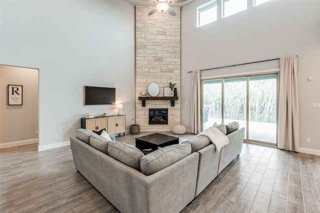 living room with a high ceiling, a fireplace, and ceiling fan