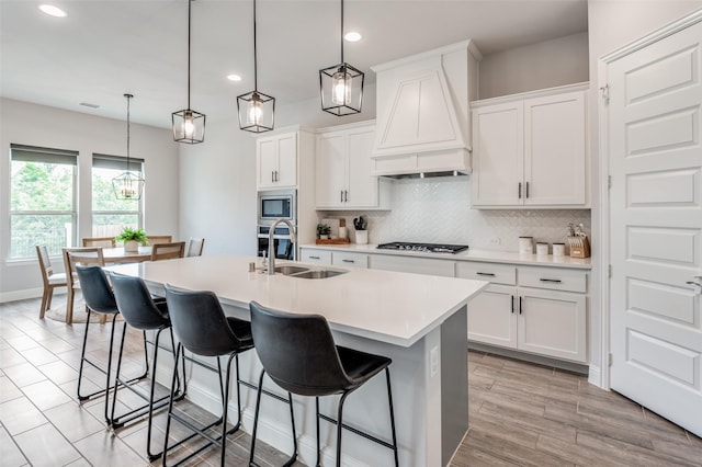 kitchen featuring white cabinets, premium range hood, and sink