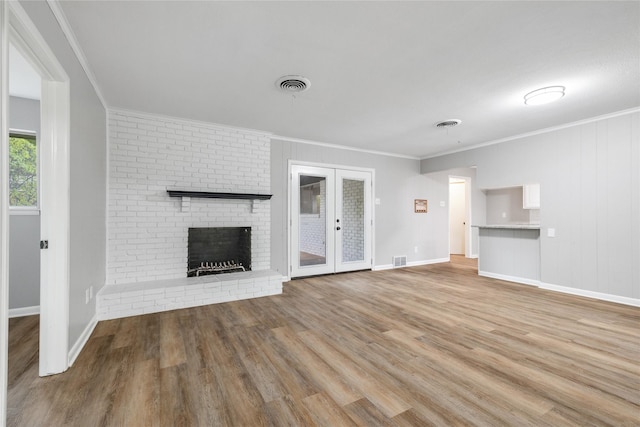 unfurnished living room featuring a fireplace, french doors, crown molding, and hardwood / wood-style floors