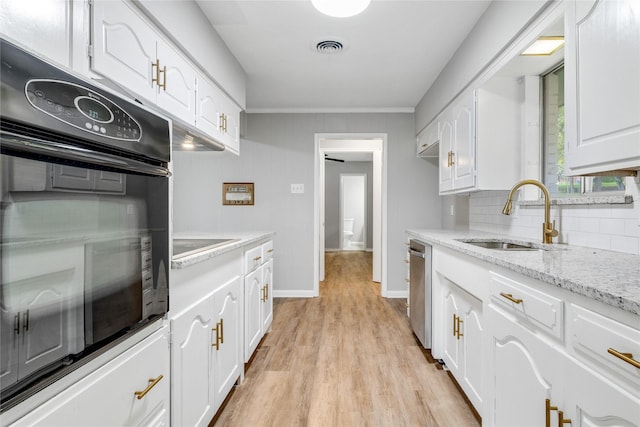 kitchen featuring sink, white cabinetry, light stone countertops, and black oven