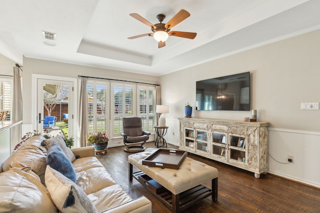 living room with ceiling fan, dark hardwood / wood-style flooring, ornamental molding, and a tray ceiling