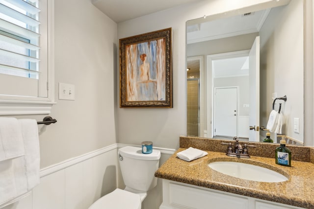 bathroom featuring toilet, crown molding, walk in shower, and vanity