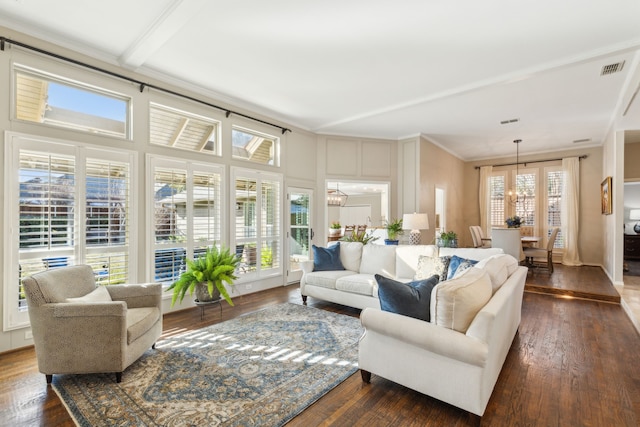 living room with dark wood-type flooring, beam ceiling, a notable chandelier, and crown molding