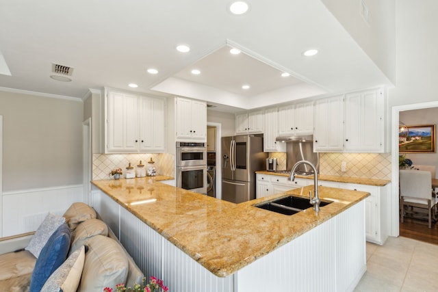 kitchen featuring kitchen peninsula, appliances with stainless steel finishes, white cabinets, light stone counters, and sink