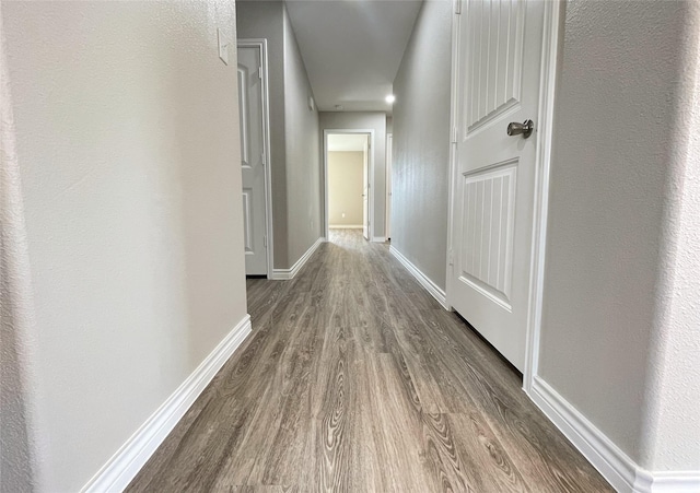 hallway featuring baseboards and wood finished floors