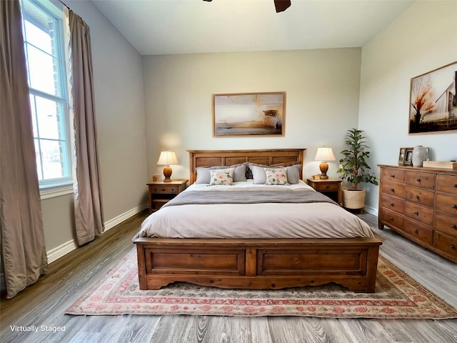 bedroom with a ceiling fan, wood finished floors, and baseboards