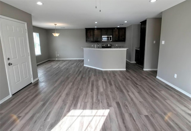 kitchen with stainless steel appliances, dark brown cabinets, and dark hardwood / wood-style flooring