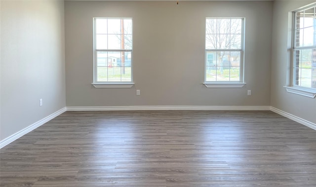 empty room featuring baseboards and dark wood finished floors