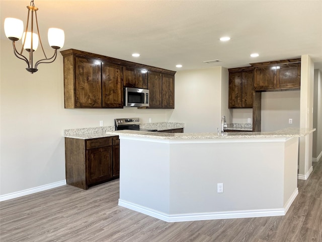 kitchen featuring dark brown cabinetry, stainless steel appliances, light wood-type flooring, and an island with sink