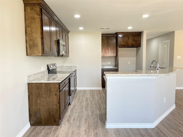 kitchen with baseboards, visible vents, light wood finished floors, stainless steel appliances, and dark brown cabinets